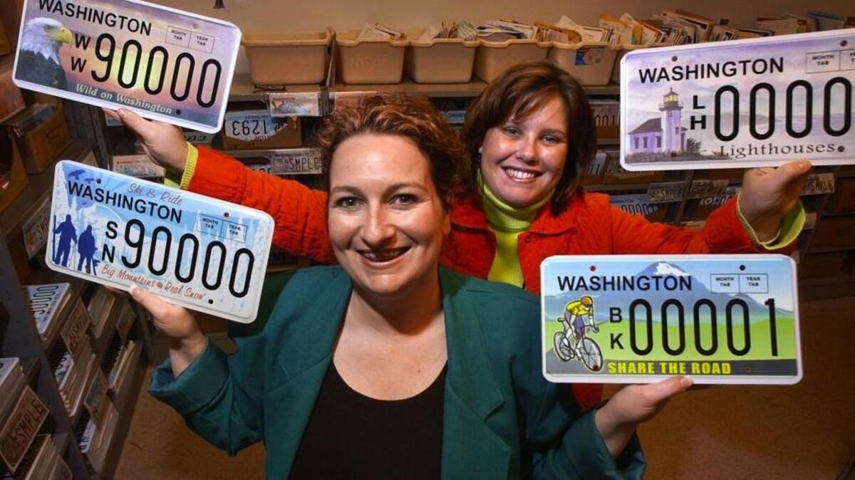 State licensing employees Jennifer Dana, front, and Alyson Chase show off some of the 18 new specialty license plates that were available to the public in 2006. More plates have since been added to Washington’s eclectic mix – including four more planned for this year.