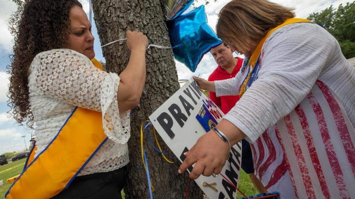 Out of town well-wishers place flowers, a sign and balloons on a tree outside of Santa Fe High School Saturday, the day after a gunman opened fire inside the school and killed 10 people.