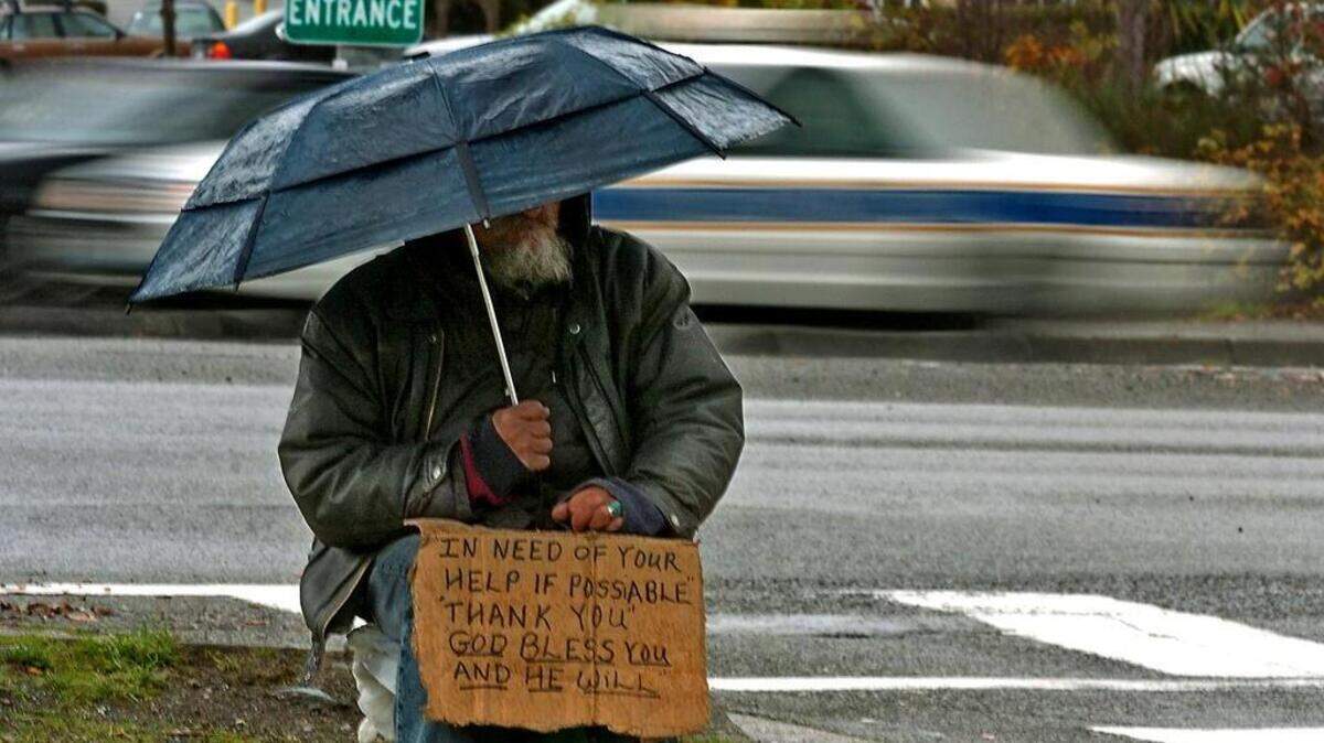 A panhandler waits for handouts at the South 72nd Street freeway exit in Tacoma.