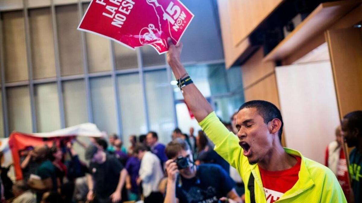 Carlos Hernandez raises a sign in celebration following the Seattle City Council's decision increasing the minimum wage in the city to $15 in 2014. Tacoma has since followed with a phased-in $12 minimum wage, approved by voters in November.