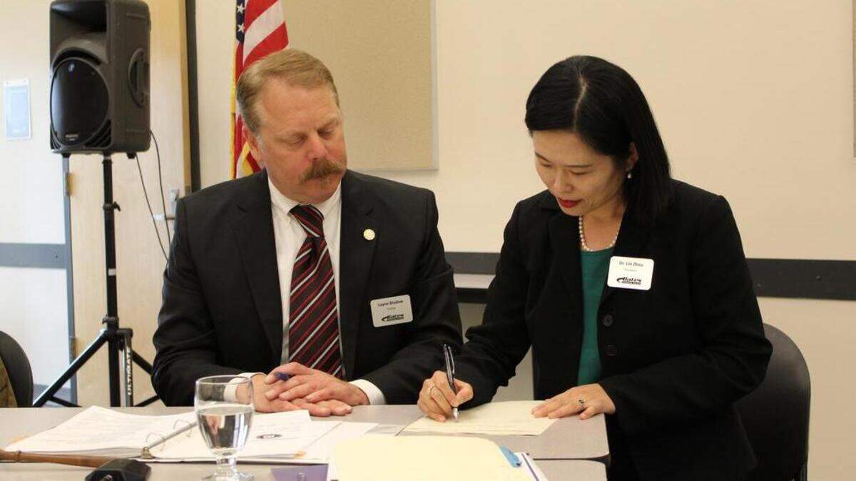 New Bates Technical College President Lin Zhou signs her two-year contract alongside Board Chairman Layne Bladow at Monday's board meeting at Bates' South Tacoma campus.