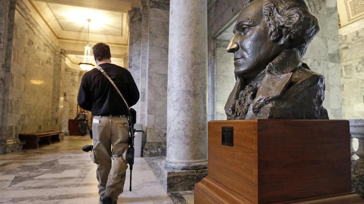 Kevin King of Graham carries an AR-15 rifle as he walks past a bust of George Washington in the Capitol rotunda in Olympia following a gun rights rally on the steps outside on Jan. 15. Lawmakers and others spoke at the rally, emphasizing legislative priorities and speaking against gun-related policies of President Barack Obama, like his recent executive actions to expand background checks to cover more firearms sold at gun shows, and elsewhere.