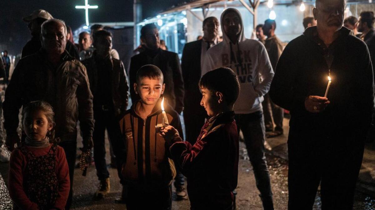 Iraqi Christians hold candles at a camp for the displaced in Irbil, northern Iraq, on Dec. 1 as they await the arrival of a convoy carrying the bodies of seven family members who drowned as they attempted to cross the Aegean Sea to Europe. They had fled Islamic State militants from their home on the plains of Nineveh last year and lived in camp in Irbil since.