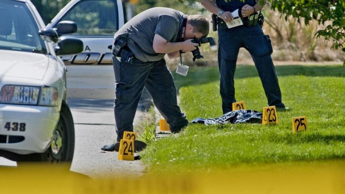 A Tacoma police photographer gathers evidence in the 3900 block of North Stevens Street at spot where a burglar who had been shot blocks away finally was stopped and given medical aid.