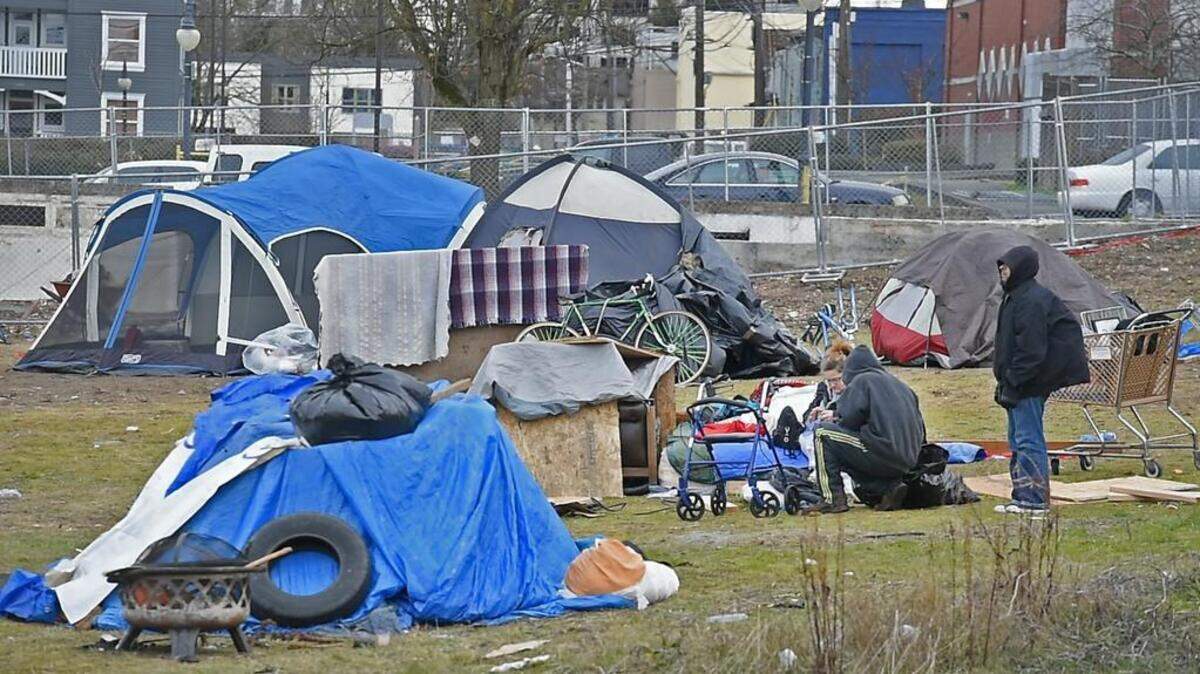 Homeless individuals huddle among their tents and possessions on a vacant lot in the 1000 block of South J Street in Tacoma's Hilltop neighborhood on Tuesday, Feb. 27, 2018.