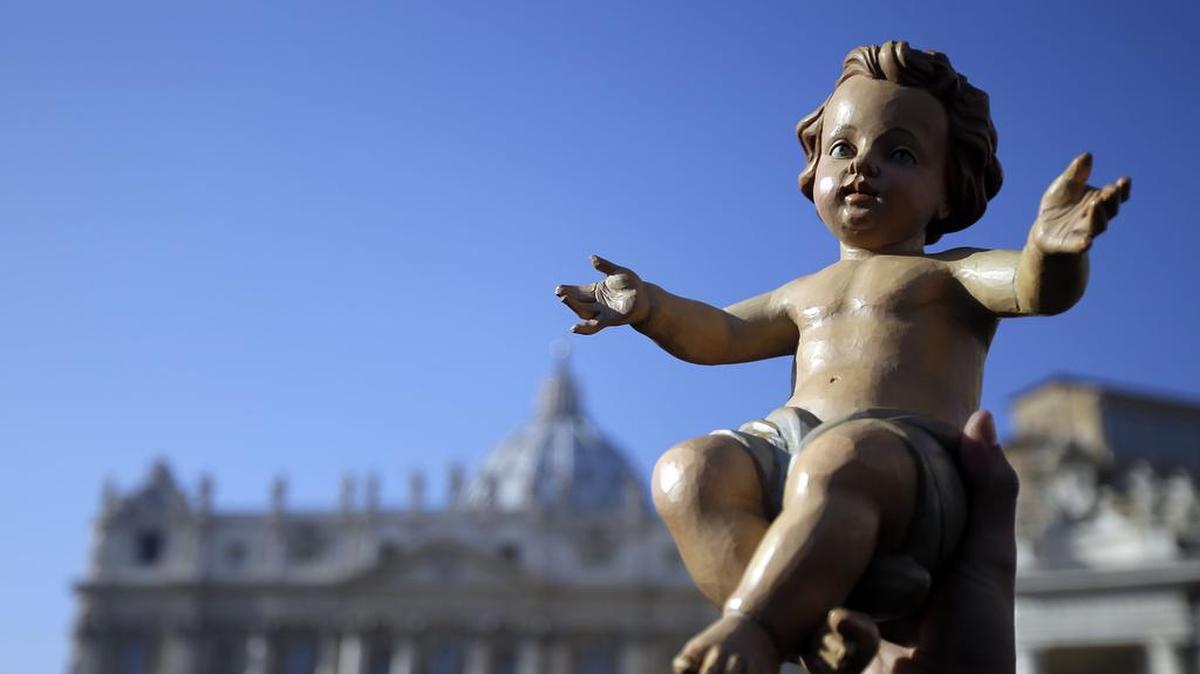 A man holds up a statue of baby Jesus prior to the start of the Angelus noon prayer in St. Peter's Square at the Vatican on Dec. 20.