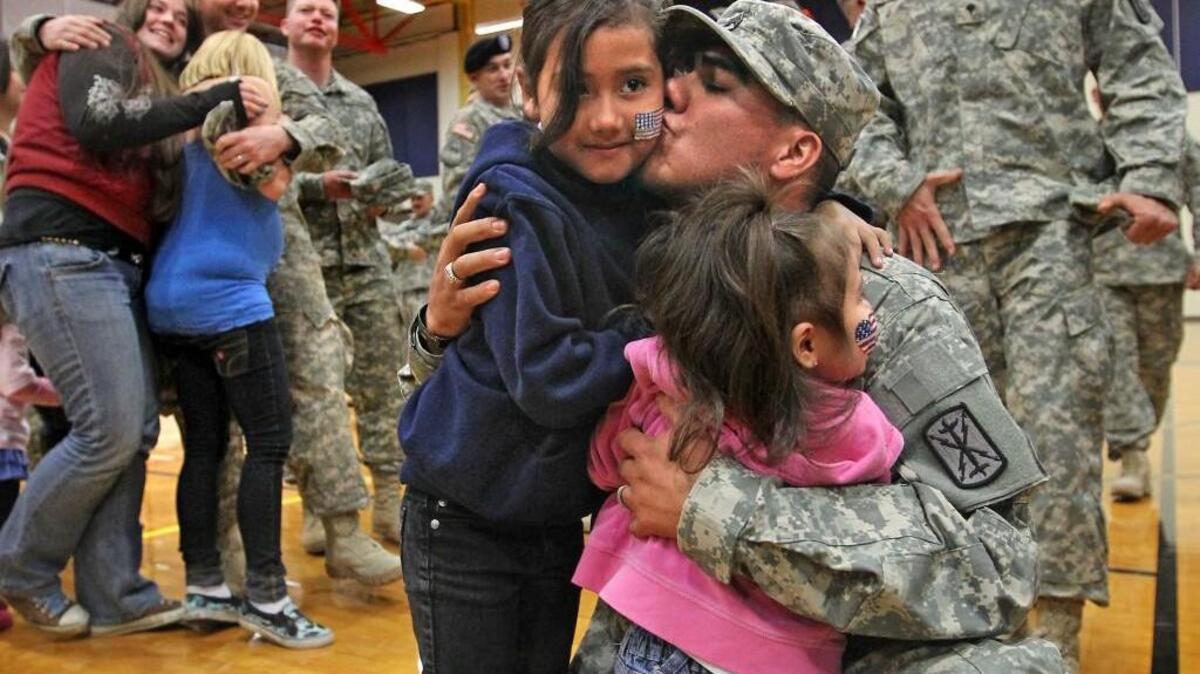 Staff Sgt. Jorge Mendoza gives hugs and kisses to his 7- and 3-year-old daughters during a homecoming for his artillery brigade, which had returned from deployment in Afghanistan in 2010.