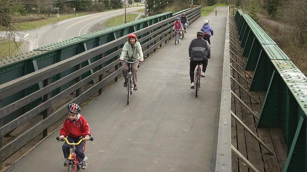 Bicycle riders roll over state Route 162 on a former railroad bridge between South Prairie and Orting in 2004, which was later connected to the Foothills Trail. Another connection to the East Pierce trail system will be funded by an increased park impact fee expected to pass the Pierce County Council. It will fund more than $55 million for park and trail projects over the next 15 years.