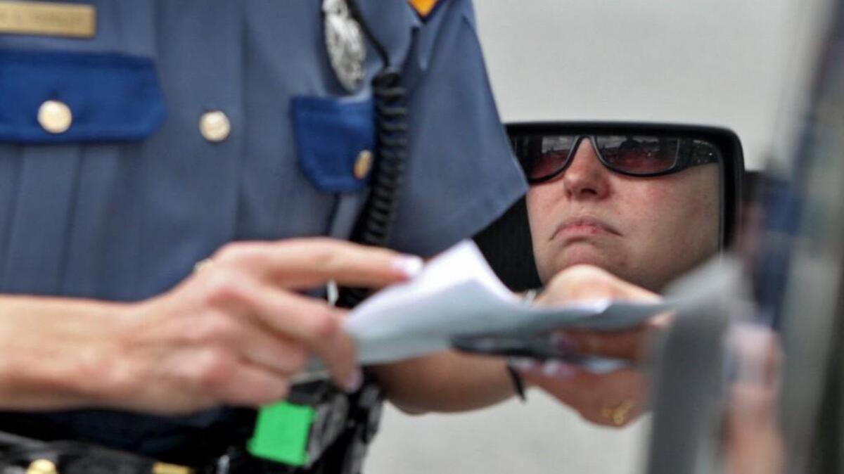 A Washington State Patrol trooper checks a driver's registration before issuing her a ticket for driving while talking on a cell phone in South Hill.