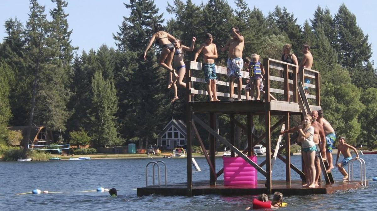 Teens jump off the floating pontoon on Lake Florence on Anderson Island. The park is reopening for the 2021 season with restrictions on parking.