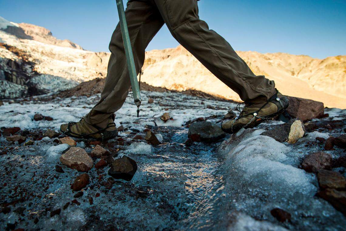 National Park Geomorphologist Paul Kennard steps over flowing meltwater on the receding Nisqually Glacier at Mount Rainier National Park in Washington state, Oct. 22, 2018. America’s glaciers are losing ice as the world warms. As they shrink and meltwater eventually declines, changes in water temperature, nutrient content and other characteristics will disrupt those natural communities. (Max Whittaker/The New York Times)