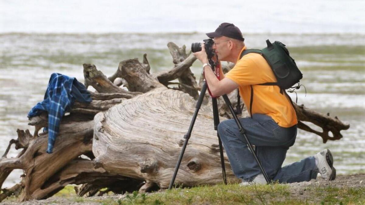 Rich Thomas from Tacoma focuses in on a beach scene after photographing the sculptured driftwood next to him during his first visit ever to Tolmie State Park in 2013. Thomas visited the park to take advantage of the waiving of the Discover Pass fees. Friday will be another free day to enter state parks.