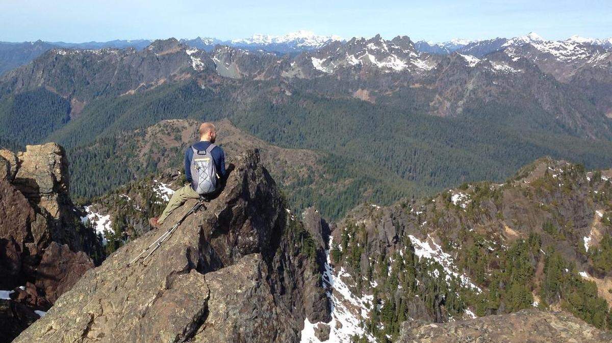 A hiker from Bremerton takes in the view of the barely snowcapped peaks of the Olympics on March 13 from the top of Mount Ellinor.