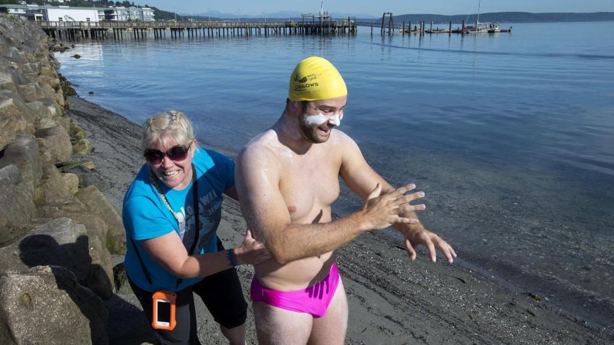 Seattle resident Andrew Malinak spreads sun block on his body with the help of fellow marathon swimmer Elaine Howley at Jack Hyde Park in Tacoma on Saturday, June 6, 2015. Malinak was attempting an 18.8-mile swim from Tacoma to West Seattle's Lincoln Park. Malinak dubbed his effort "The Return of Bert Thomas Swim" in honor of the notable long-distance swimmer from Tacoma.