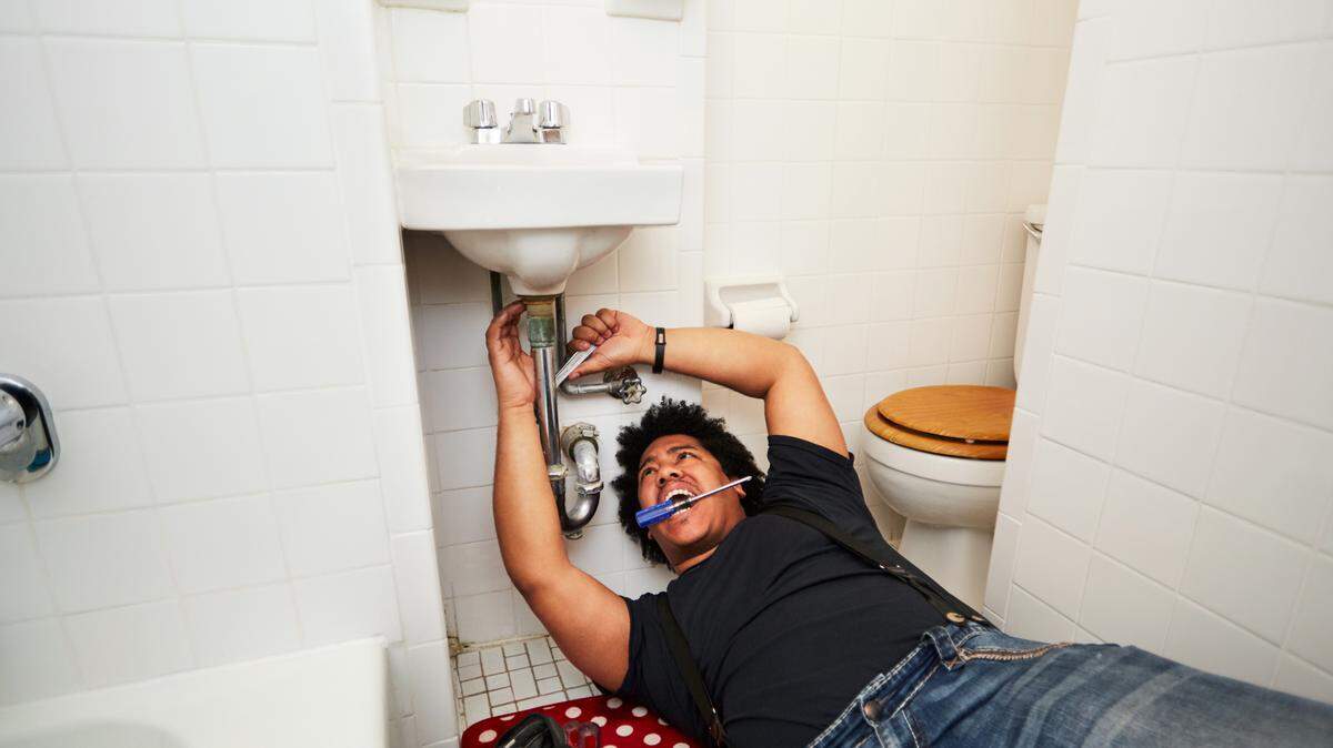 Man working on pipes under a sink