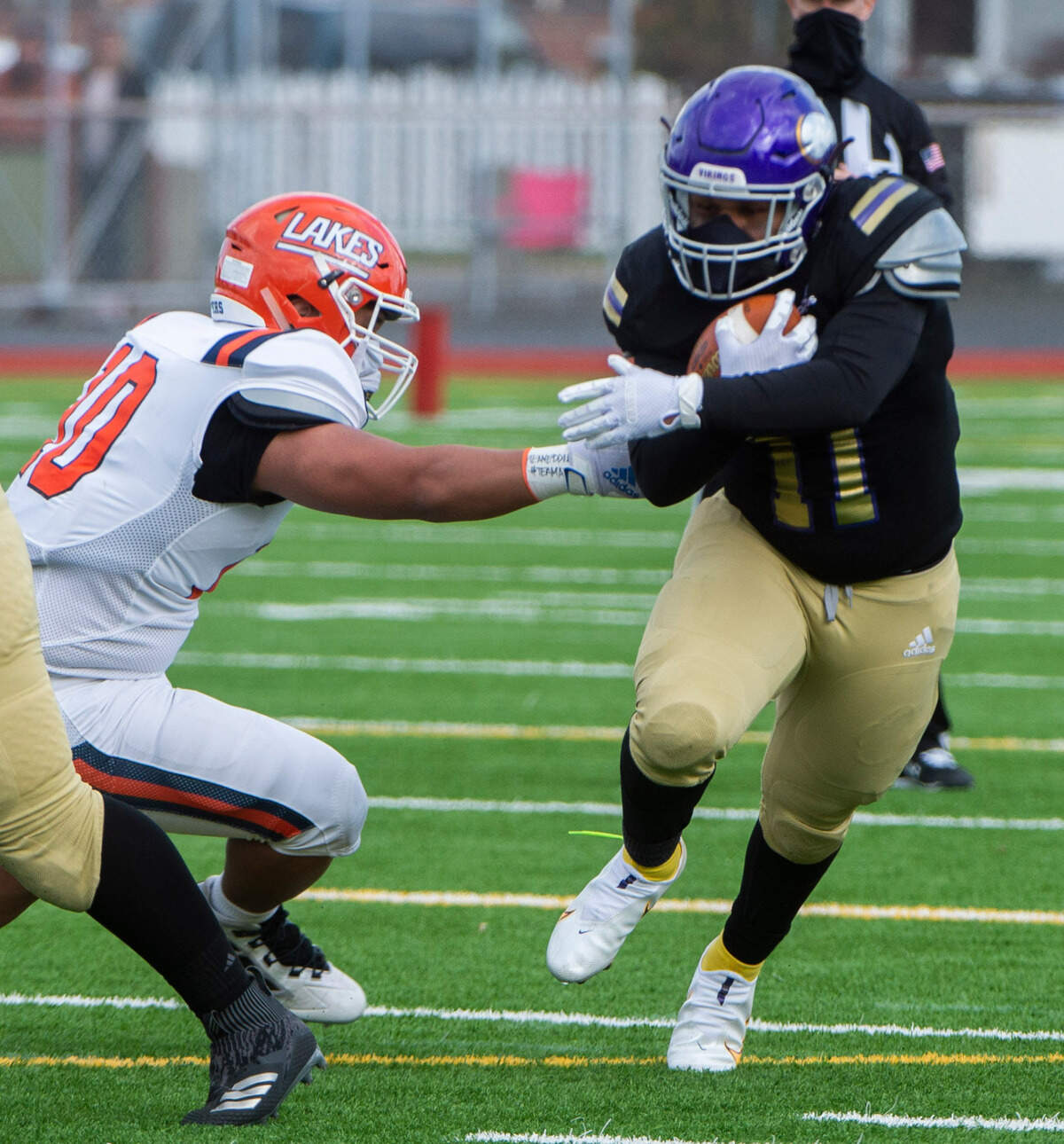 Puyallup running back Ziere Ford runs through the arm tackle of Lakes defender Mykah Koke’-Filimana as the Vikings rolled to a 44-16 victory over the Lancers at Sparks Stadium in Puyallup Saturday, Feb. 27, 2021.