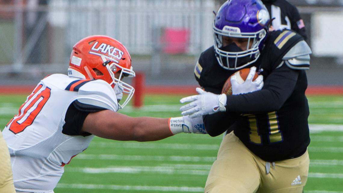 Puyallup running back Ziere Ford runs through the arm tackle of Lakes defender Mykah Koke’-Filimana as the Vikings rolled to a 44-16 victory over the Lancers at Sparks Stadium in Puyallup Saturday, Feb. 27, 2021.