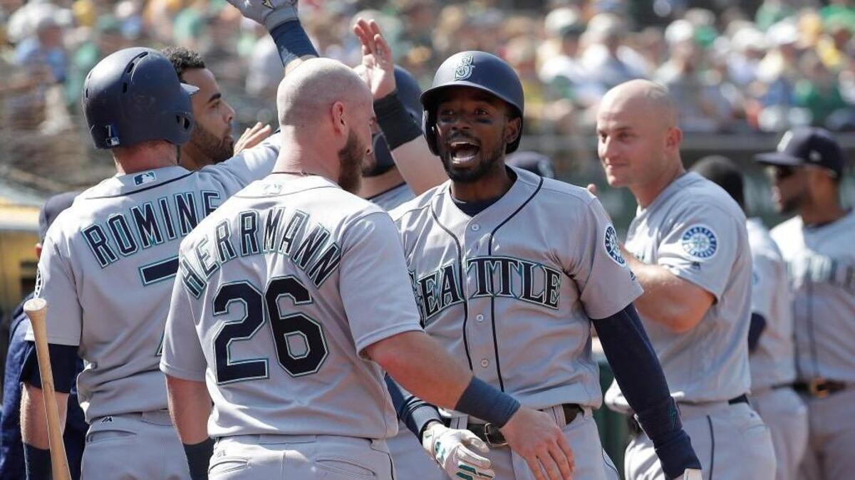 Seattle Mariners’ Dee Gordon, center right, is congratulated by teammates after hitting a two-run home run against the Oakland Athletics during the 12th inning of a baseball game in Oakland, Calif., Wednesday, Aug. 15, 2018. (AP Photo/Jeff Chiu)