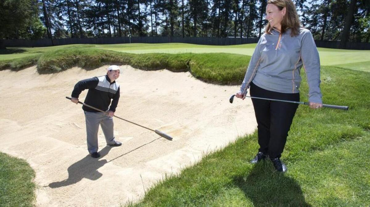 Sara Griffin laughs after her husband Chris was assigned raking duty at Tacoma Country & Golf. Both are golf pros at the club. Photo taken in Tacoma on Thursday, May 12, 2016.