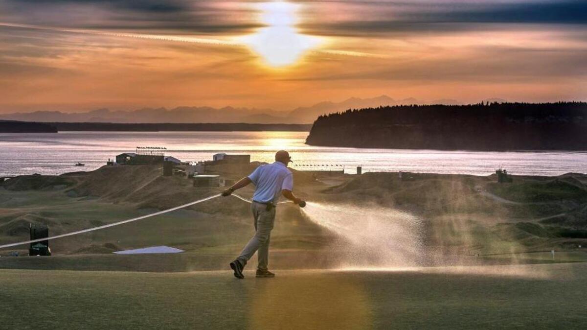 A golf course crew waters the grass late in the evening to prepare for the final day pf practice at the 115th U.S. Open at Chambers Bay Tuesday June 17, 2015.