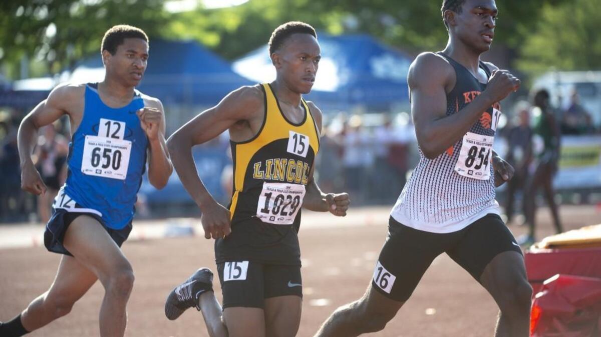 Lincoln’s James Mwaura (15) runs between Gig Harbor’s Peter Smith (12) and Kennewick’s Johan Correa during the 3A boys 1600-meter final on the opening day of the state track meet at Mount Tahoma High School in Tacoma on Thursday, May 24, 2018.