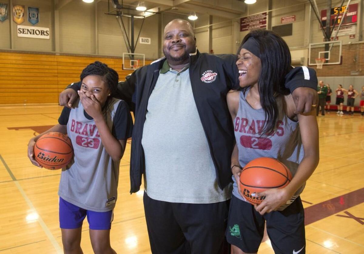 Bethel High sisters Tiarra, left, and Tianna Brown crack up while posing with their dad, Tim. The Brown sisters are the top scores for the Braves, and their dad, who is on a heart transplant list, is the team’s assistant coach.