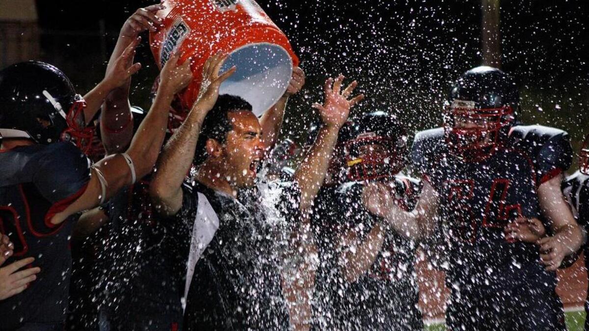King's coach Jim Shapiro is soaked by his players at Woolsey Stadium in Shoreline during the filming of a USA Football commercial back in July, 2014. King’s will play Royal for the Class 1A state football championship Saturday.