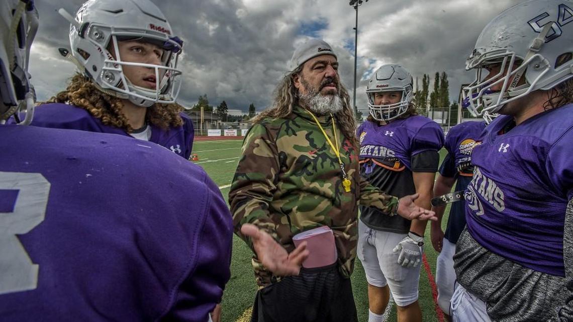 Sumner High School football coach Keith Ross, center, breaks down a play with his players including his son, starting quarterback Luke Ross. Luke is the three-year starting quarterback of maybe three of Sumner's best teams in school history. His father is a former All-American linebacker at Central Washington University.