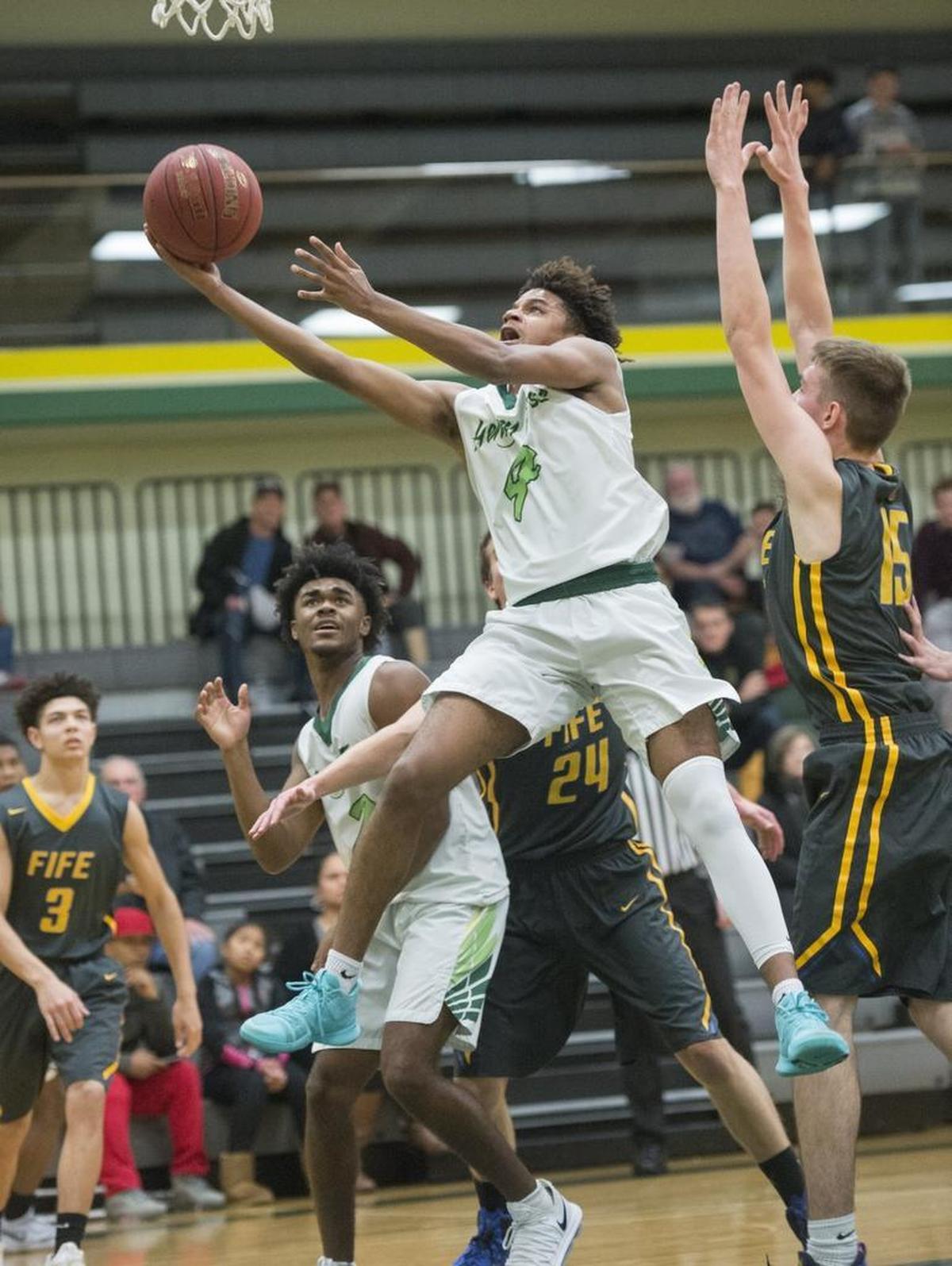Falcons forward Damani Kelly slips past the defense of Fife's Brian Mitchell for a score Foss guard during the Falcons' 66-48 rout of the Trojans in Tacoma on Tuesday, Jan. 16, 2018.