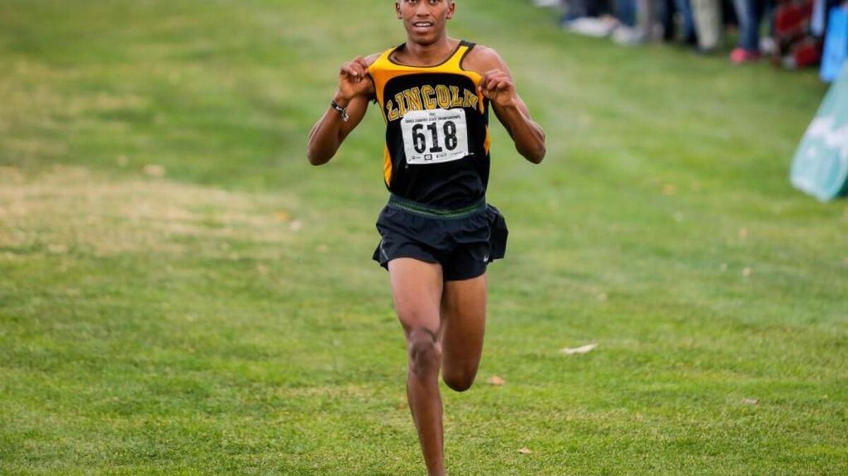 Lincoln’s James Mwaura celebrates his inevitable win by popping his jersey during the boys 3A cross country state championship at Sun Willows Golf Course in Pasco on Saturday, Nov. 4.