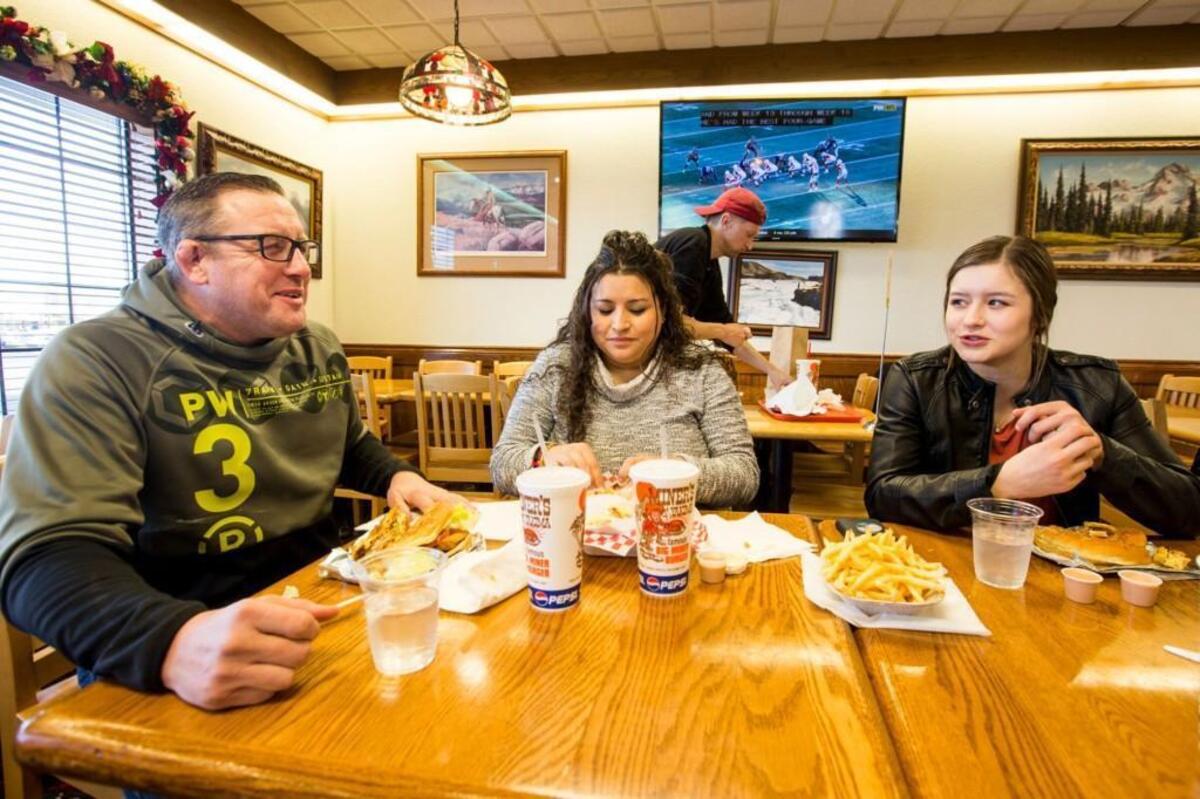 Cameron Guerin laughs with her father, Rich, and mother Julie while having a weekly "cheat" lunch with friends at Miner's Drive-In in Yakima, Wash. on Sunday, Dec. 31, 2017. Guerin sticks to a strict nutrition regimen, but Sundays allow for her to have a full meal with her family.