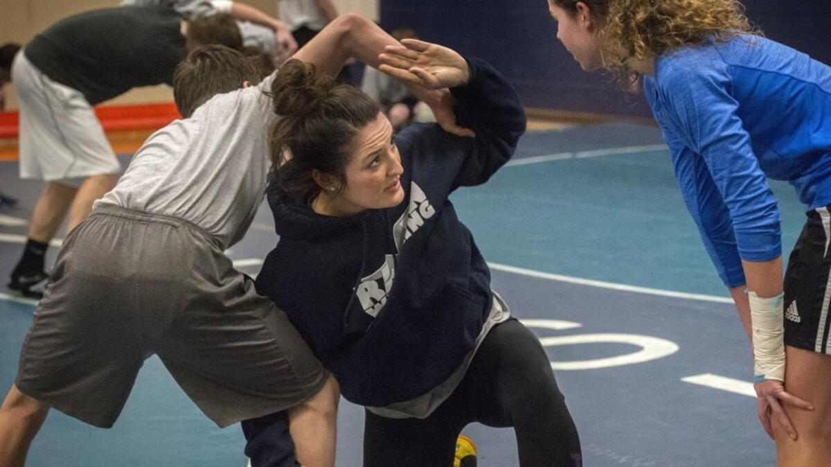 Auburn Riverside girls wrestling coach Amberle Montgomery, center, demonstrates a move to the school’s only girl wrestler, freshman Kaitlyn Packer, during a practice last week at in Auburn.