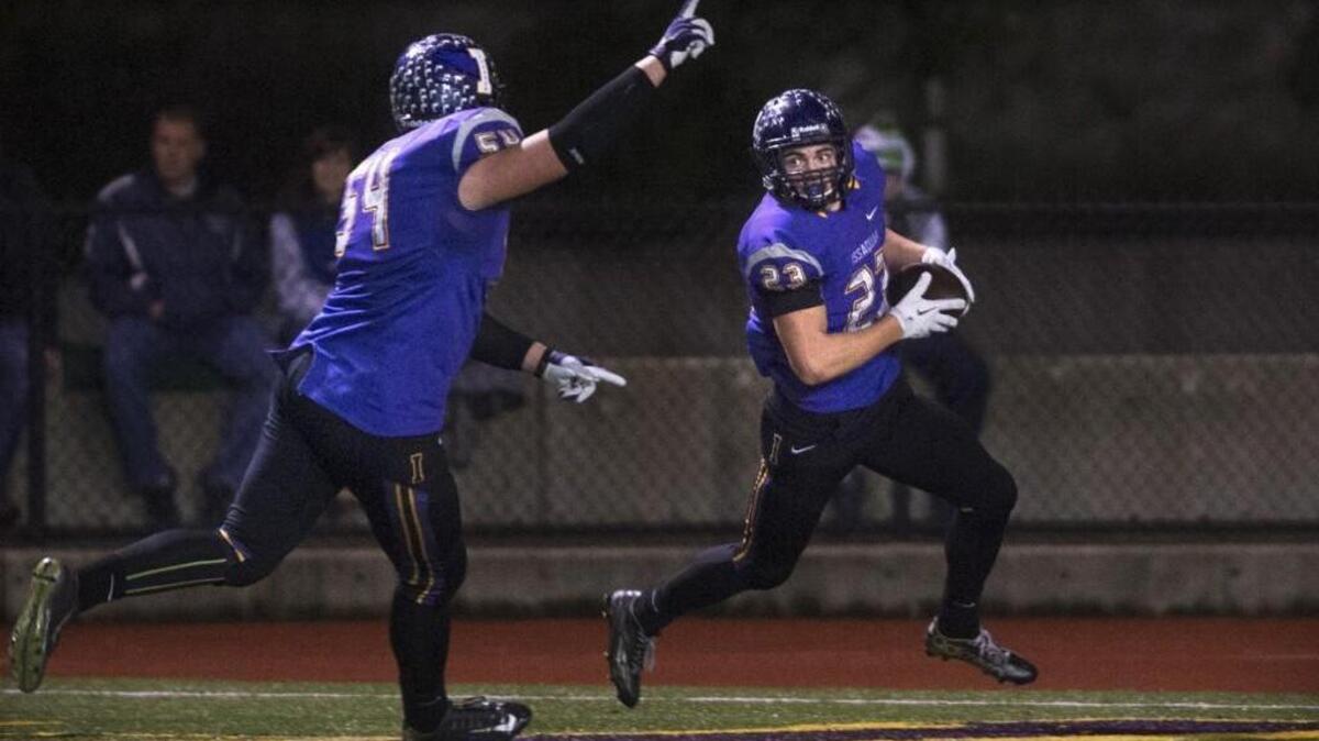 Issaquah's Connor Smith (left) celebrates as teammate Conner Pederson scores a pick-six touchdown during Friday night's 4A football district playoff game against the Olympia Bears at Gary Moore Stadium in Issaquah on Nov. 6, 2015.