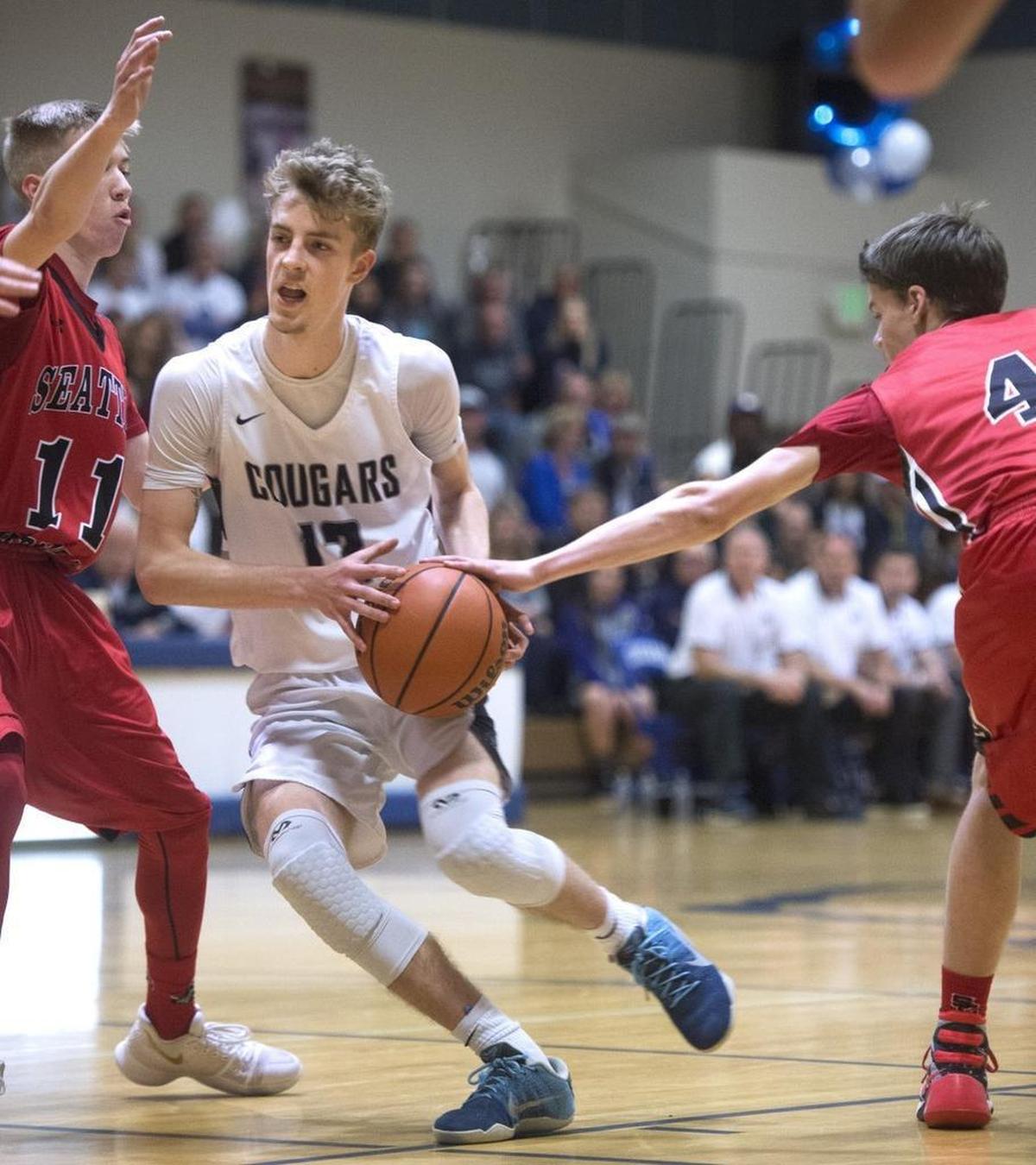 Cascade Christian's Noah Wilkins drives the lane against Seattle Christian defenders Connor Knack (11) and Spencer Howell during Tuesday night's boys basketball game at Cascade Christian High School in Puyallup, Feb. 6, 2018.