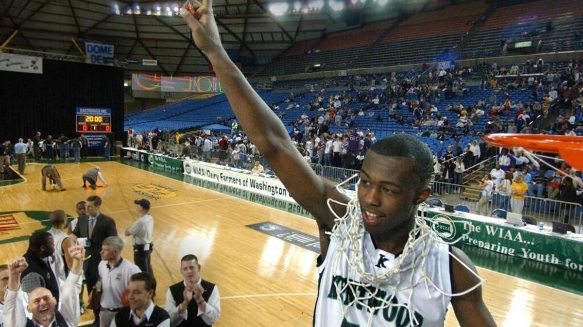 After Kentwood's Rodney Stuckey finished cutting the net down, he celebrates the State Championship win. Saturday, March 13, 2004 (Lui Kit Wong/The News Tribune)