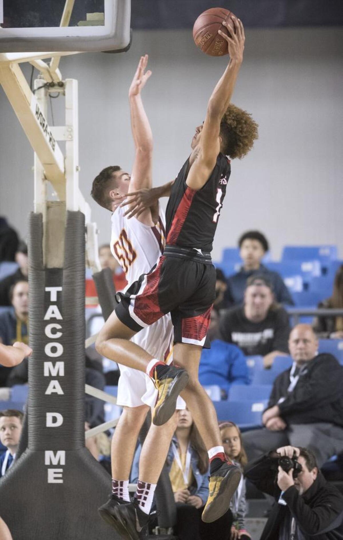 Wilson's Emmitt Matthews Jr. throws down a dunk over Capital defender Chris Schnellman during their opening-round game of 3A boys basketball state tournament game.