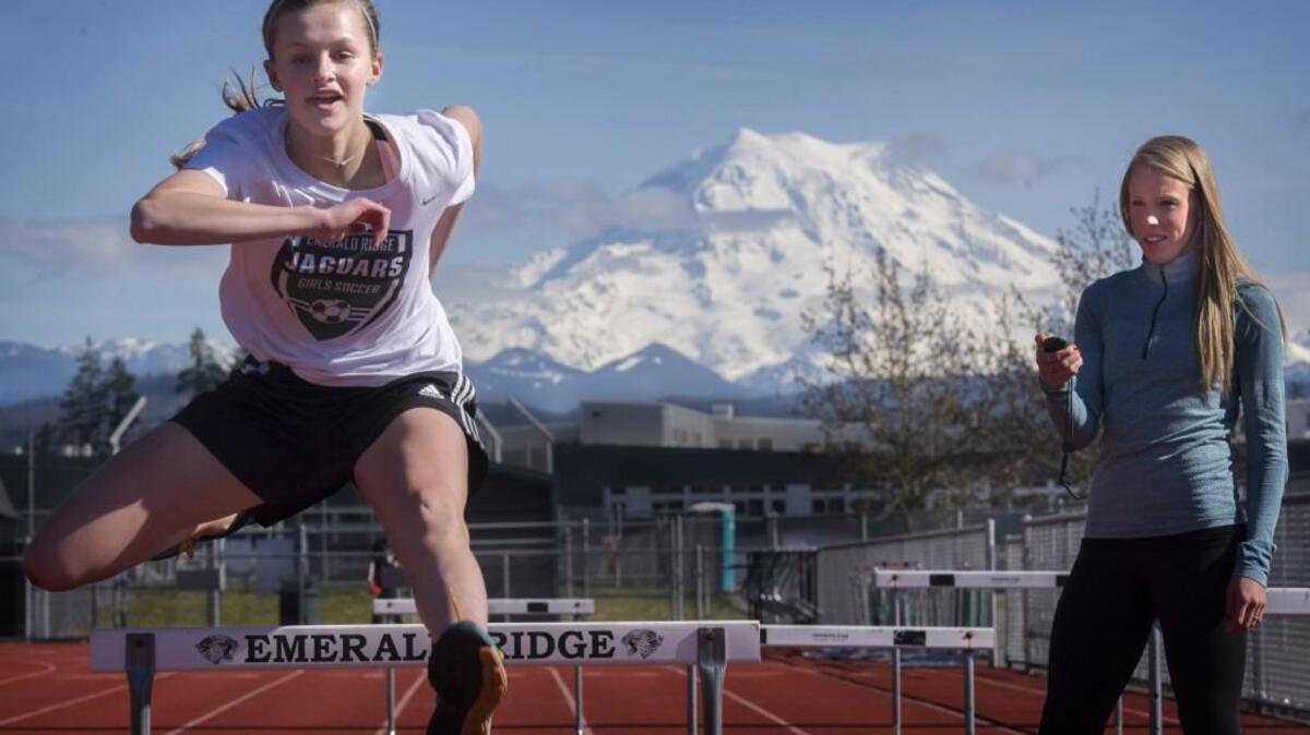 Emerald Ridge track coach Kayla Stueckle, right, watches her younger sister, Karlee, practices her hurdling during practice at Emerald Ridge High School on Thursday. Kayla thinks Karlee could someday break her hurdles records at the school.