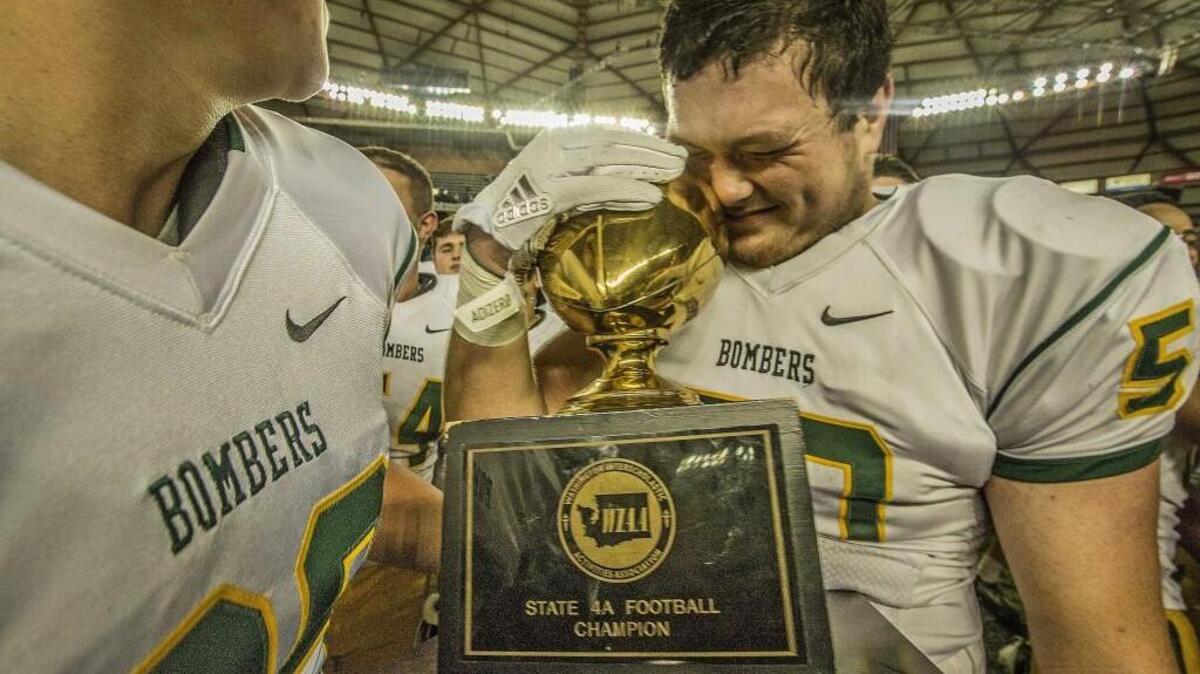 Richland lineman Jacobe Lee (50) hugs the trophy after the Bombers edge the Falcons of Woodinville 28-21 to capture the 4A Washington state football championship in the Tacoma Dome Saturday, Dec. 2, 2017.