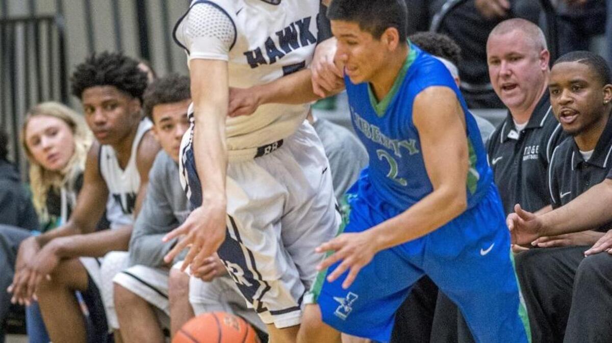 Tre'Vonne Dorfner of River Ridge High School battles with David Rodriguez of Liberty in front of the River Ridge bench in a AA boys basketball playoff game at Foss High School in Tacoma, February 17, 2016.