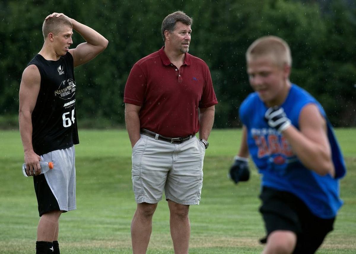 Former Seattle Seahawk center Robbie Tobeck center, checks in with son Mason left, as they watched Madden Tobeck, right, during a junior high practice at Cascade Chrsitian High School Monday Aug. 26, 2013. Mason was a tight end and linebacker at Cascade Christian High School and now plays at Utah State University. Madden is now a senior at Cascade Christian. Dean J. Koepfler / Staff Photographer