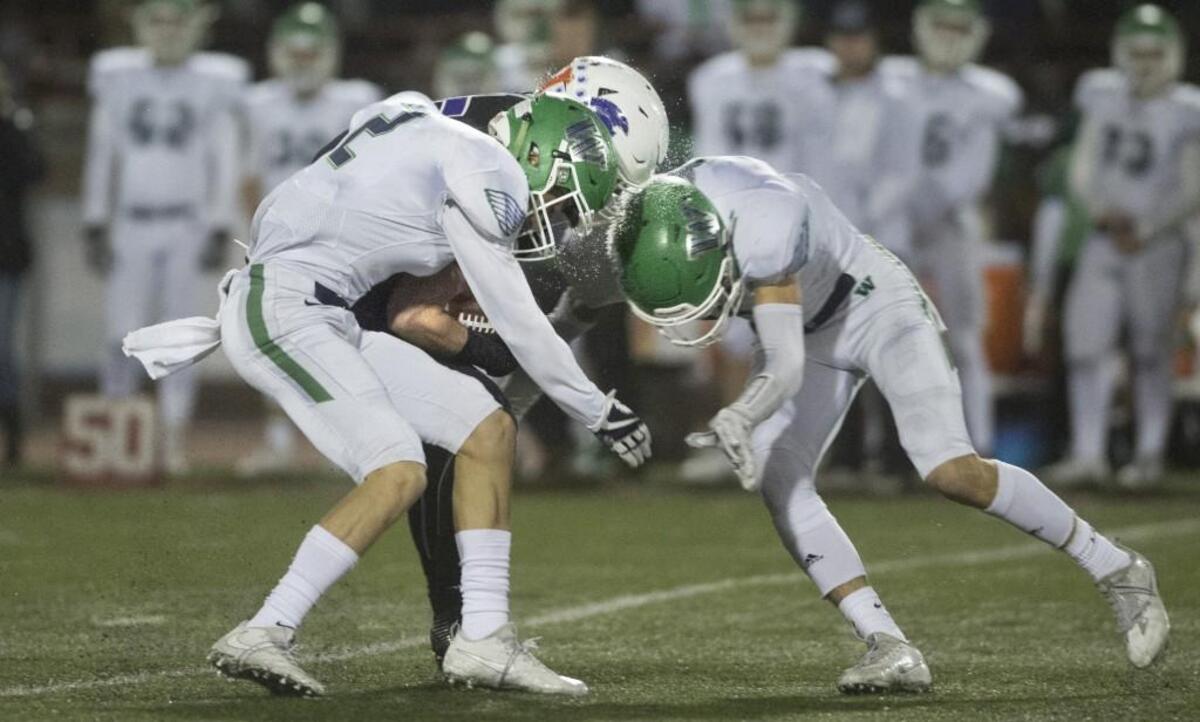 Woodinville defenders Seth Pregler (left) and Nash Fouch force a fumble from Sumner running back Alex Fraser during the 4A state football semifinal at Sparks Stadium in Puyallup on Nov. 25, 2017. Woodinville recovered the fumble.