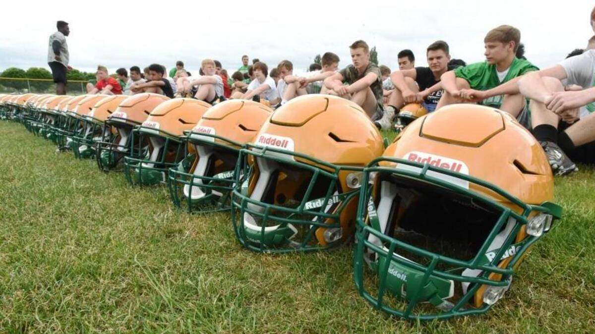 Tumwater players sit next to a row of new helmets that were donated to the team by the Seattle Seahawks and United Health Care.