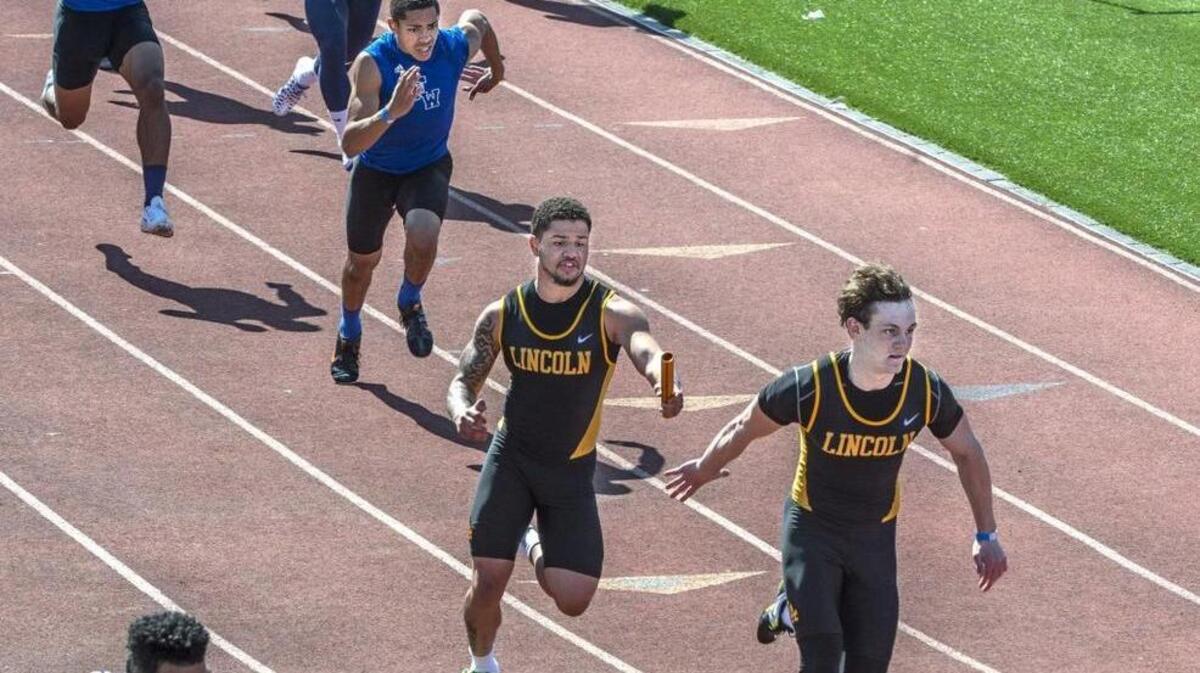 Lincoln’s Walker Flynn, right, reaches back for the baton from teammate Xzavier Weston during the boys 4x400 relay. The Abes won the race.