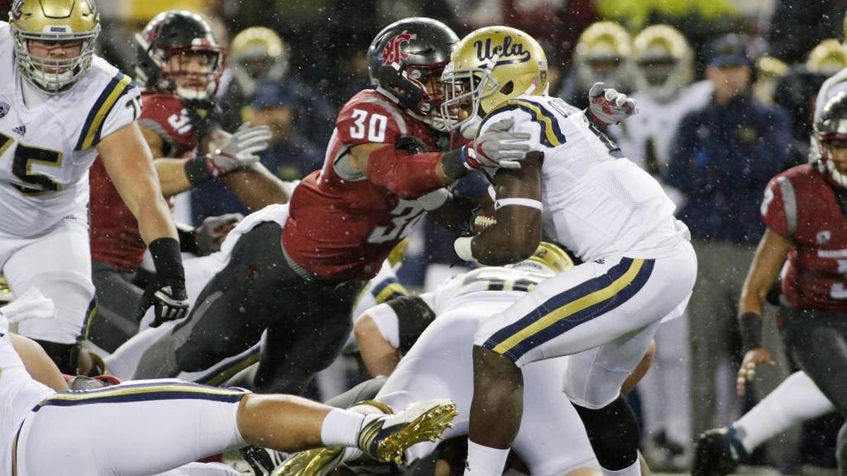 Washington State defensive lineman Nnamdi Oguayo (30) brings down UCLA running back Bolu Olorunfunmi (4) during a 27-21 victory over the Bruins on Saturday, the Cougars’ fourth straight win.