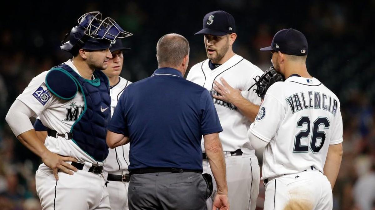 James Paxton indicates a problem with his left pectoral area in a discussion with trainer Rick Griffin.
