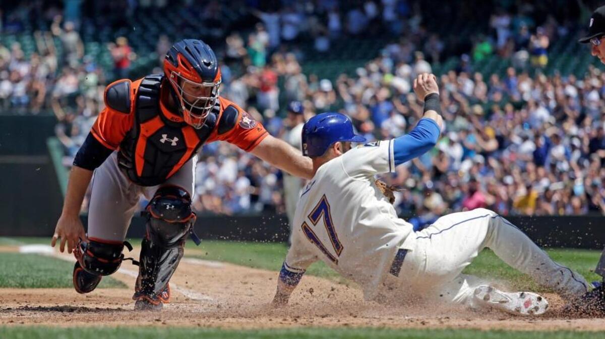 Seattle Mariners’ Mitch Haniger (17) slides past on a tag by Houston Astros catcher Evan Gattis in the second inning Sunday in Seattle. Haniger was called out.