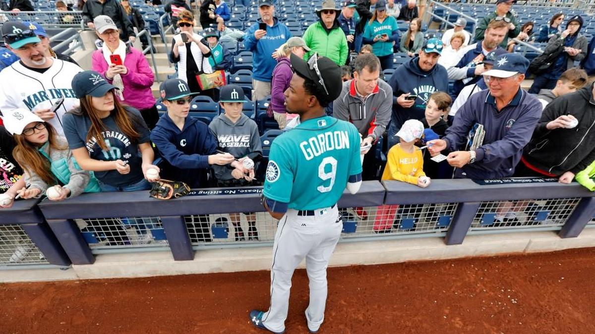 Seattle Mariners center fielder Dee Gordon gives autographs to fans before a baseball spring exhibition game against the San Diego Padres, Friday, Feb. 23, 2018, in Peoria, Ariz.