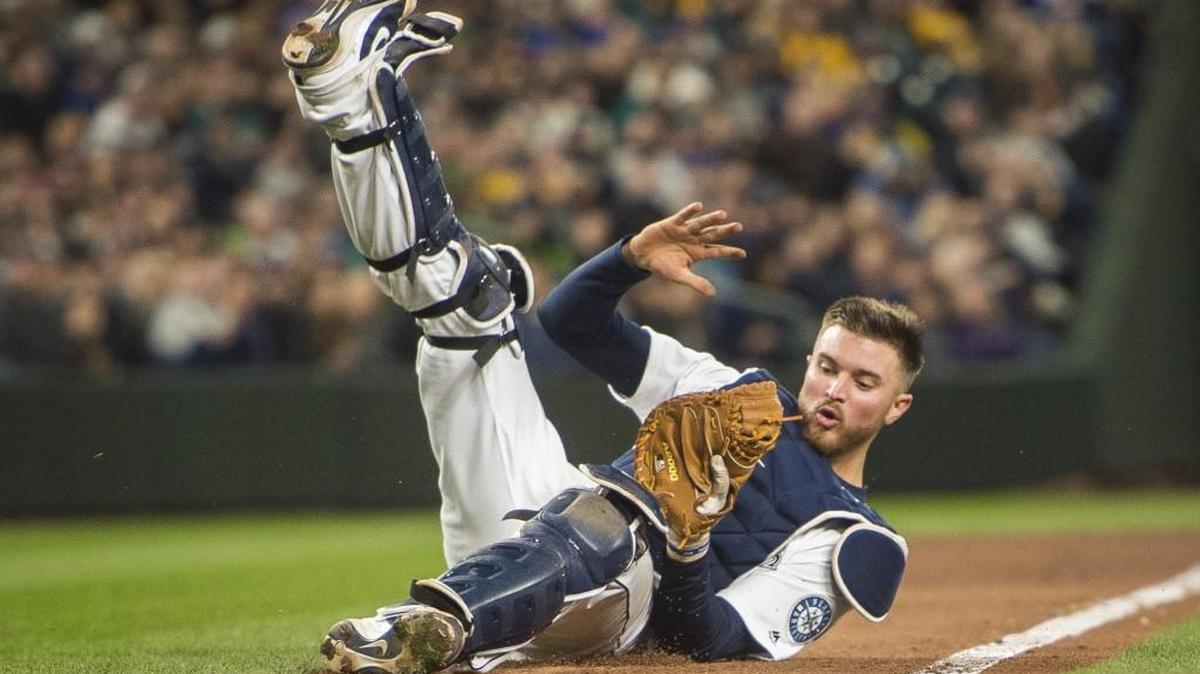 Catcher Mike Marjama falls over making a catch in the fifth inning. The Seattle Mariners played the Cleveland Indians in a baseball game on Opening Day at Safeco Field in Seattle, Wash., on Wednesday, March 28, 2018.