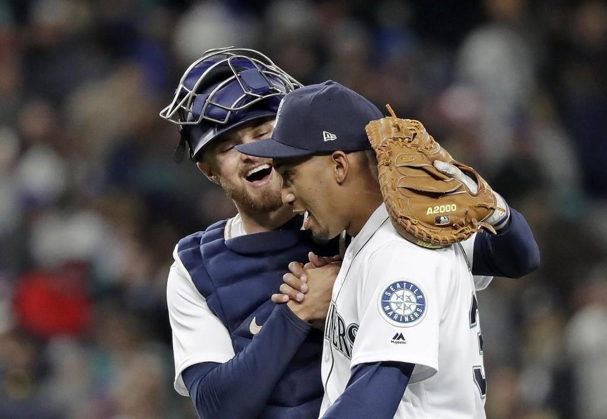 Seattle Mariners catcher Mike Marjama, left, embraces closing pitcher Edwin Diaz after the team's 2-1 win over the Cleveland Indians in a baseball game Thursday, March 29, 2018, in Seattle. (AP Photo/Elaine Thompson)