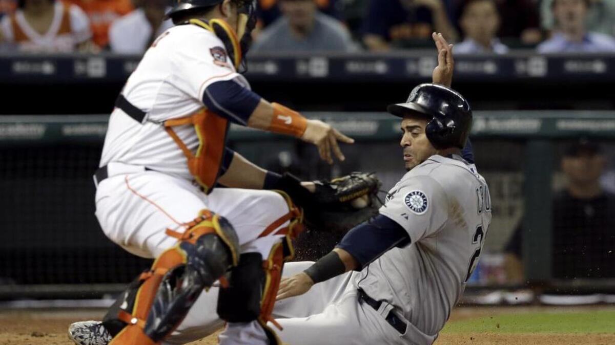 
Astros catcher Hank Conger tags Seattle’s Nelson Cruz out at home plate in the seventh inning on Wednesday. Cruz strained his quadriceps that inning while running the bases and will likely not play versus Oakland this weekend.
